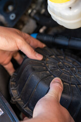 close up of hands of a caucasian male car mechanic removing the air filter cover of an engine