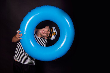 Handsome guy sailor and lifebuoy. Blue inflatable circle. Black background.