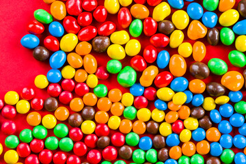 Fototapeta na wymiar M&M's candy on the red background, colorful candy, multicolored gradient