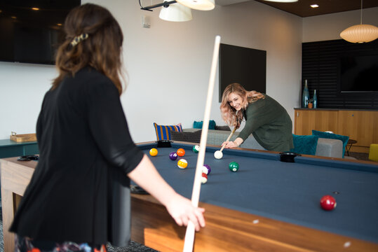 Two women playing pool together in apartment