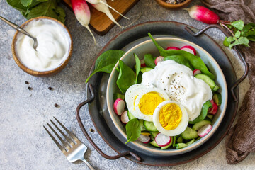 Fresh spring food, healthy vegan lunch bowl. Spinach, cucumber, radish salad and boiled eggs with sour cream. Copy space.