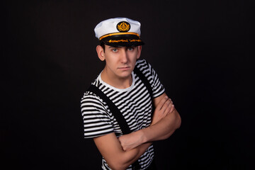Handsome guy on a black background. Captain of a sea vessel. Positive and negative emotions.