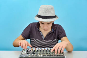A boy controls a mixing console in a music studio.