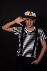 Fototapeta premium Handsome guy on a black background. Captain of a sea vessel. Positive and negative emotions.