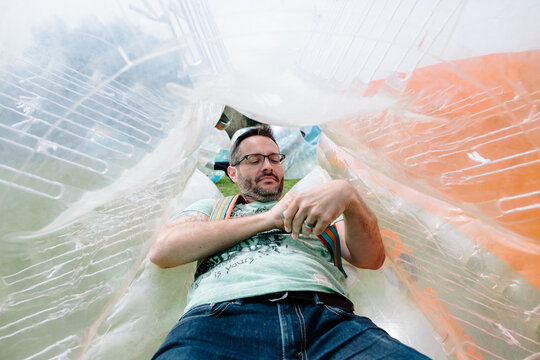 Man suits up and adjust straps of his bubble soccer inflatable ball