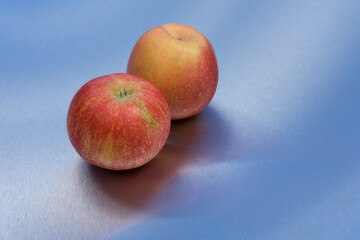 two delicious red apples and blue clean metallic background