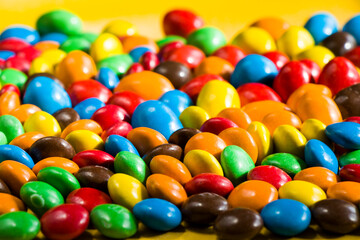 Fototapeta na wymiar M&M's candy on the yellow background, colorful candy, multicolored gradient