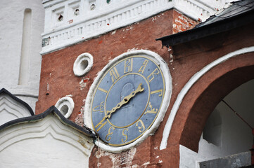 Old large clock on the wall of a red brick building. Architecture and sights.