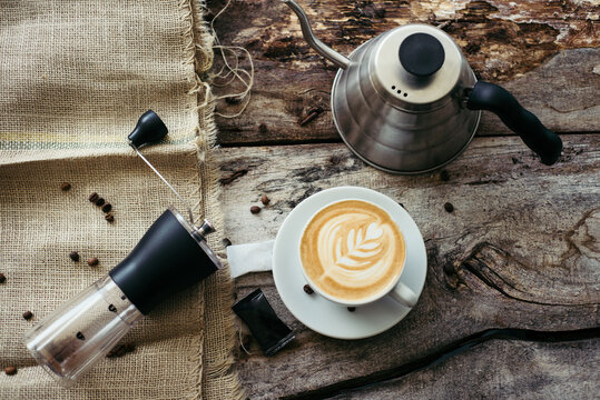 Manual grinder, kettle and creative coffee on the old table.