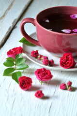 cup of tea and rose flowers and buds on white wood