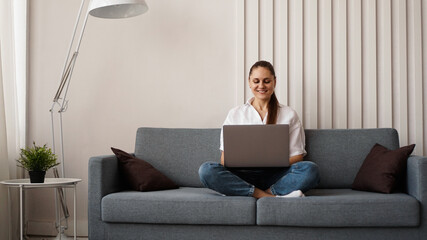 Woman working on laptop from home or student studying from home or freelancer. Modern business woman in a white shirt and jeans.