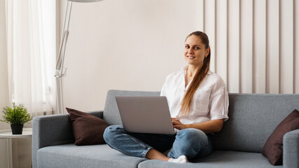 Woman working on laptop from home or student studying from home or freelancer. Modern business woman in a white shirt and jeans.