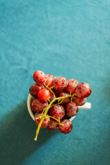 Bowl with purple grapes on blue tablecloth