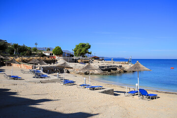 Fototapeta na wymiar Beach with sun loungers and sun umbrellas in Ksamil resort