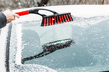 Removing snow from car. Clean car window in winter from snow, winter brush and scraper clearing car...