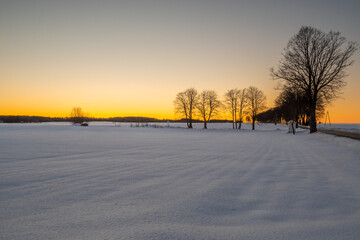 Winter rural landscape, snow covered field during sunset