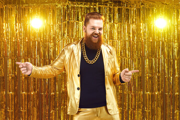 Funny uninhibited plus size young man with ginger beard and mustache in golden suit with bling gold...