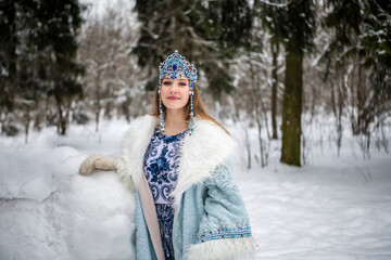 Russian beauty in a national costume with a red fox in a winter snowy forest 