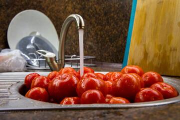 Closeup of washed red tomatoes under running water