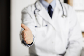 Unknown male doctor offering helping hand in clinic near his working place, closeup. Perfect medical service in hospital. Medicine and healthcare concept