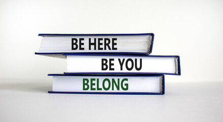 Belong symbol. Books with words 'be here, be you, belong' on beautiful white table, white...