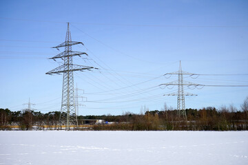Energieversorgung: Hochspannungsmasten / Masten einer Stromleitung an einem sonnigen Wintertag,...