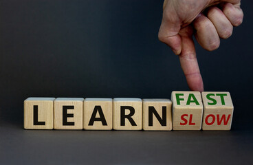 Learn slow or fast symbol. Businessman turns wooden cubes and changes words 'learn slow' to 'learn fast'. Beautiful grey background, copy space. Business and learn slow or fast concept.