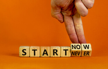 Start now or never symbol. Businessman turns wooden cubes and changes words 'start never' to 'start now'. Beautiful orange background, copy space. Business and start now or never concept.