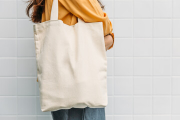 Woman is holding tote bag canvas fabric for mockup blank template. - 413881390