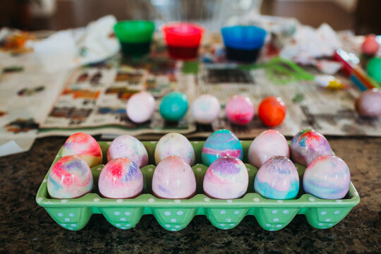 Dozen colorful dyed easter eggs sitting on kitchen counter