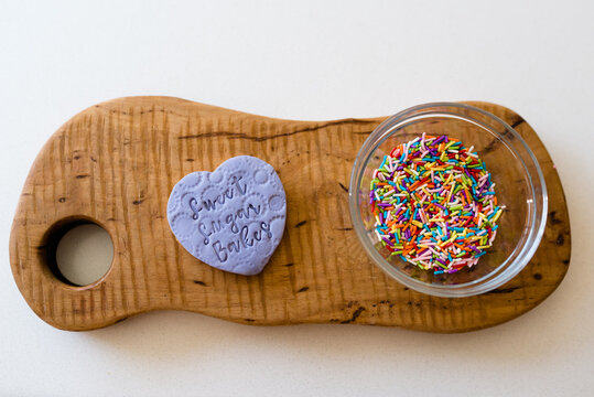 Flat lay of a purple decorated bookie with a bowl of sprinkles
