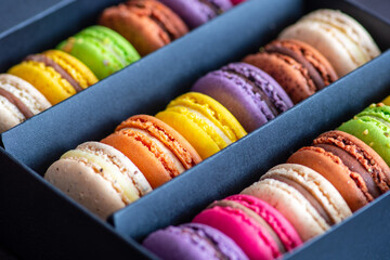 Various colorful macarons or French macaroons in a row in a gift box, sweet meringue-based...