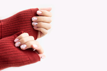 Pastel beige manicure on the light background. Manicured nails and soft hands skin with copy space. Woman's hands in warm sweater.
