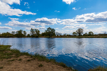 Landscape of Odra river with grass and bushes in front of at cloudy sunny day