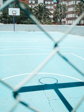 Empty blue basketball court with buildings in background