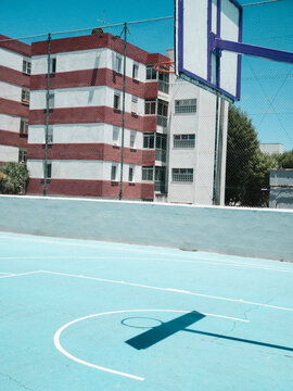 Basketball goal on blue court against colorful buildings