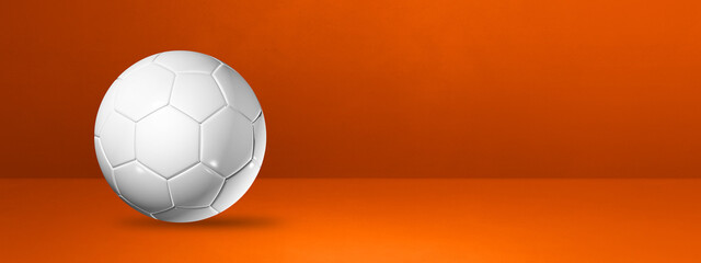 White soccer ball on a orange studio banner