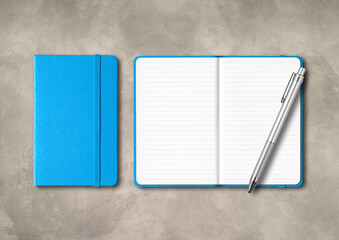Blue closed and open lined notebooks with a pen on concrete background