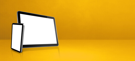 Mobile phone and digital tablet pc on yellow office desk. Background banner