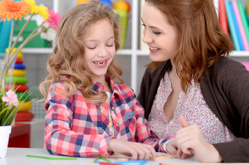 Fototapeta premium little cute girl with mother drawing at the table at home