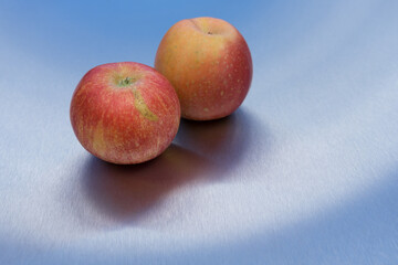Pair of two tasty red apples and reflection on blue clean metallic background