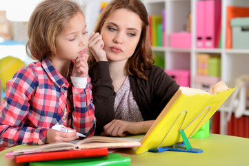Portrait of a beautiful little cute girl  with mother doing homework
