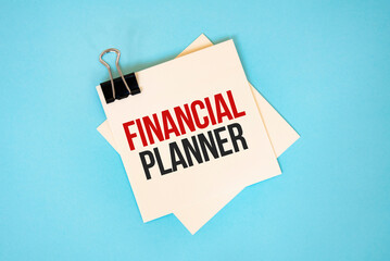 Text FINANCIAL PLANNER on sticky notes with copy space and paper clip isolated on red background.Finance and economics concept.