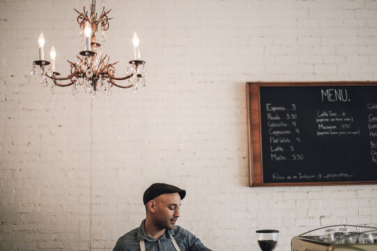 Male owner standing against wall in cafe