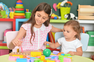 Two little girls playing with colorful plastic blocks