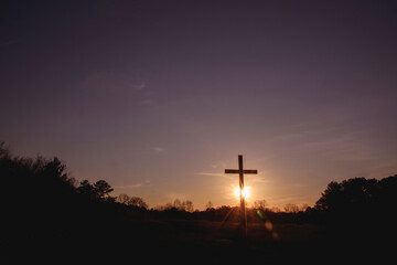 Silhouette cross on field against sky during sunset