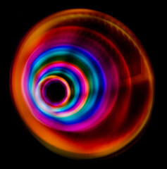 Multicolored light circles of different colors, yellow blue, red, blurred circle on a black background, photo was taken with a long exposure when the lanterns of rainbow colors were twisted