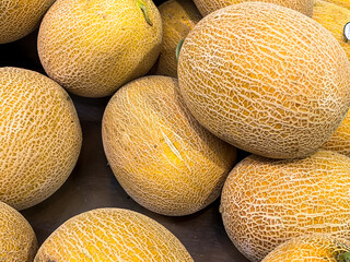 Large yellow melons on a rack in a modern supermarket.