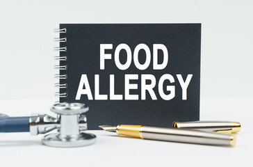 On a white background lies a stethoscope, a pen and a black notebook with the inscription - FOOD ALLERGY