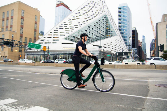 Full length of man riding bicycle on street by buildings in city